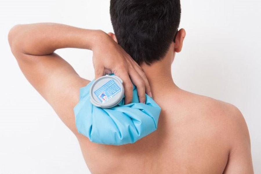 Person placing a warm compress pack on neck and shoulder area at home