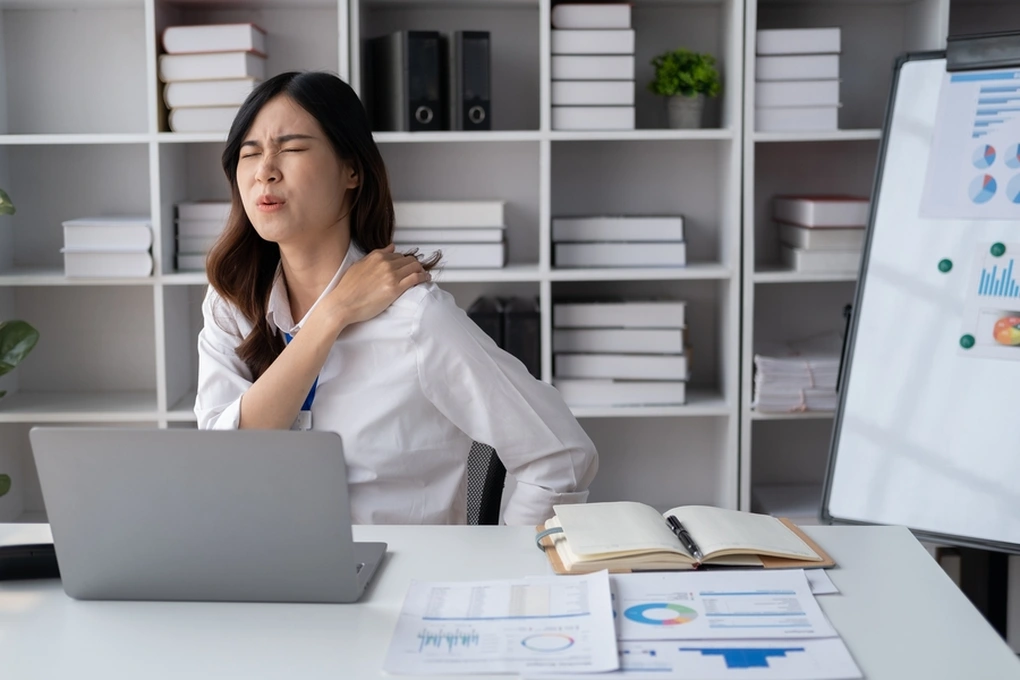 Office worker holding neck and shoulder due to pain after sitting at computer for hours